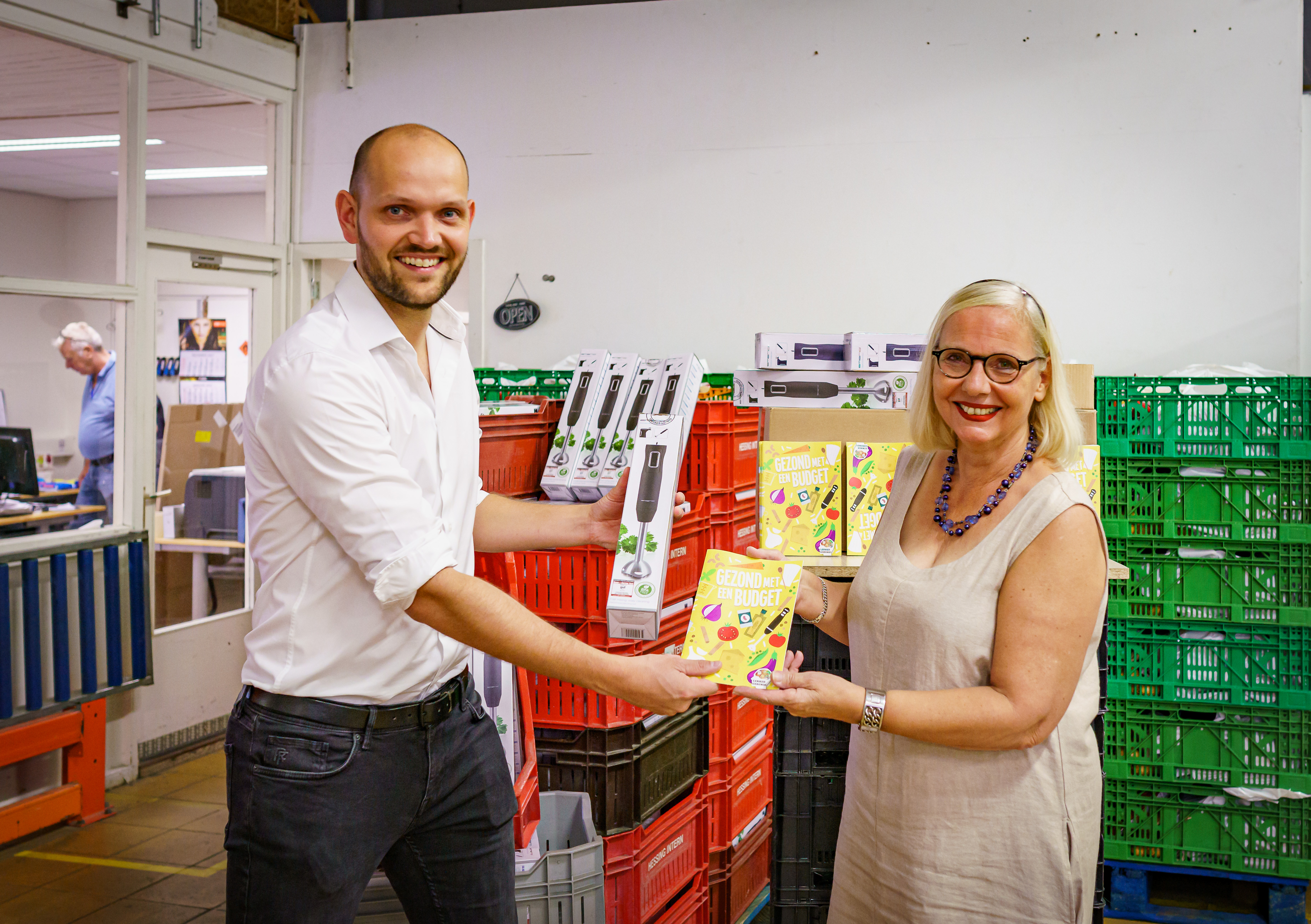 Wethouder Wouter Struijk en Dini Bonninga met boek 'Gezond met een budget' en staafmixer in handen 